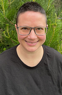 A woman with short hair and glasses smiles at the camera