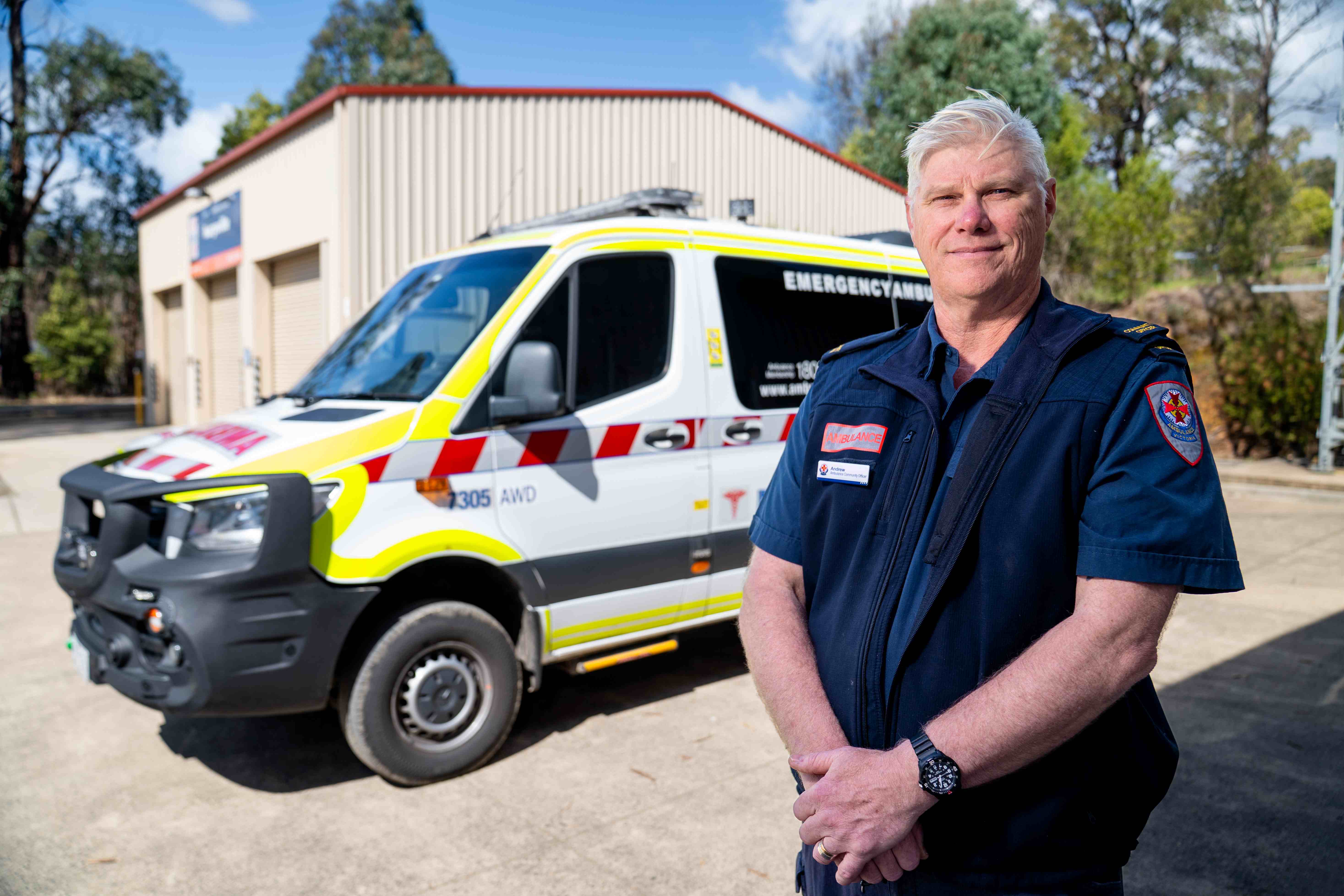 A man in a paramedic uniform standing in front of an ambulance. 