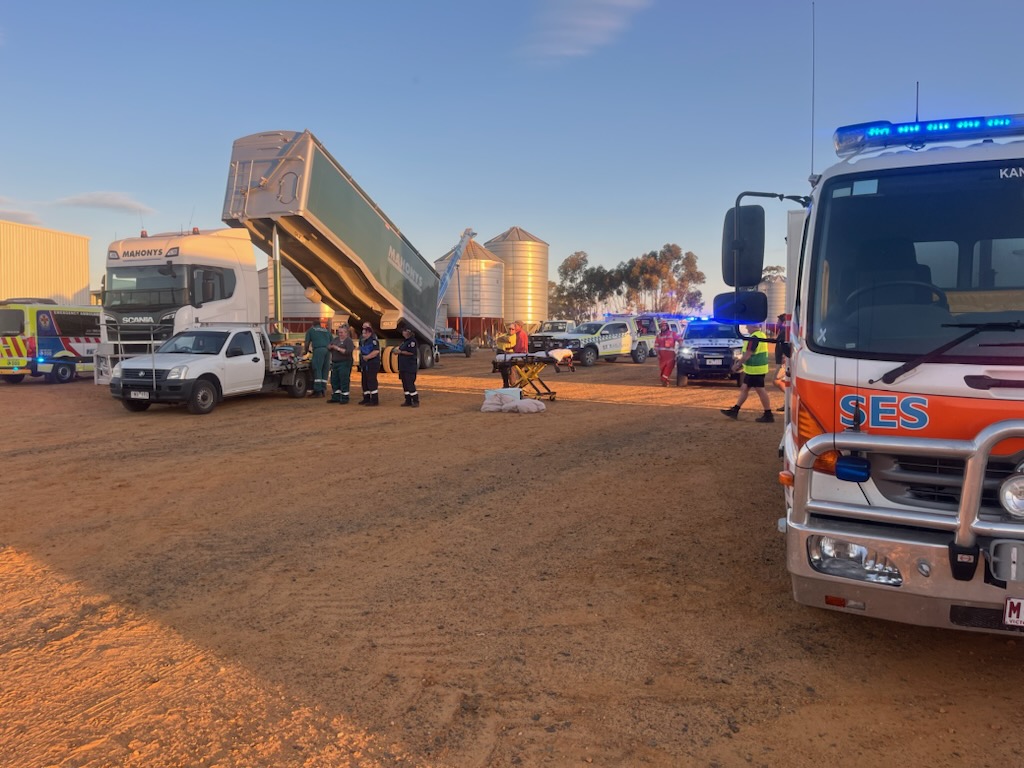Emergency service vehicles surround a truck at a farm.