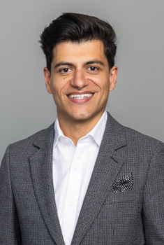 A man in business clothes smiles at the camera