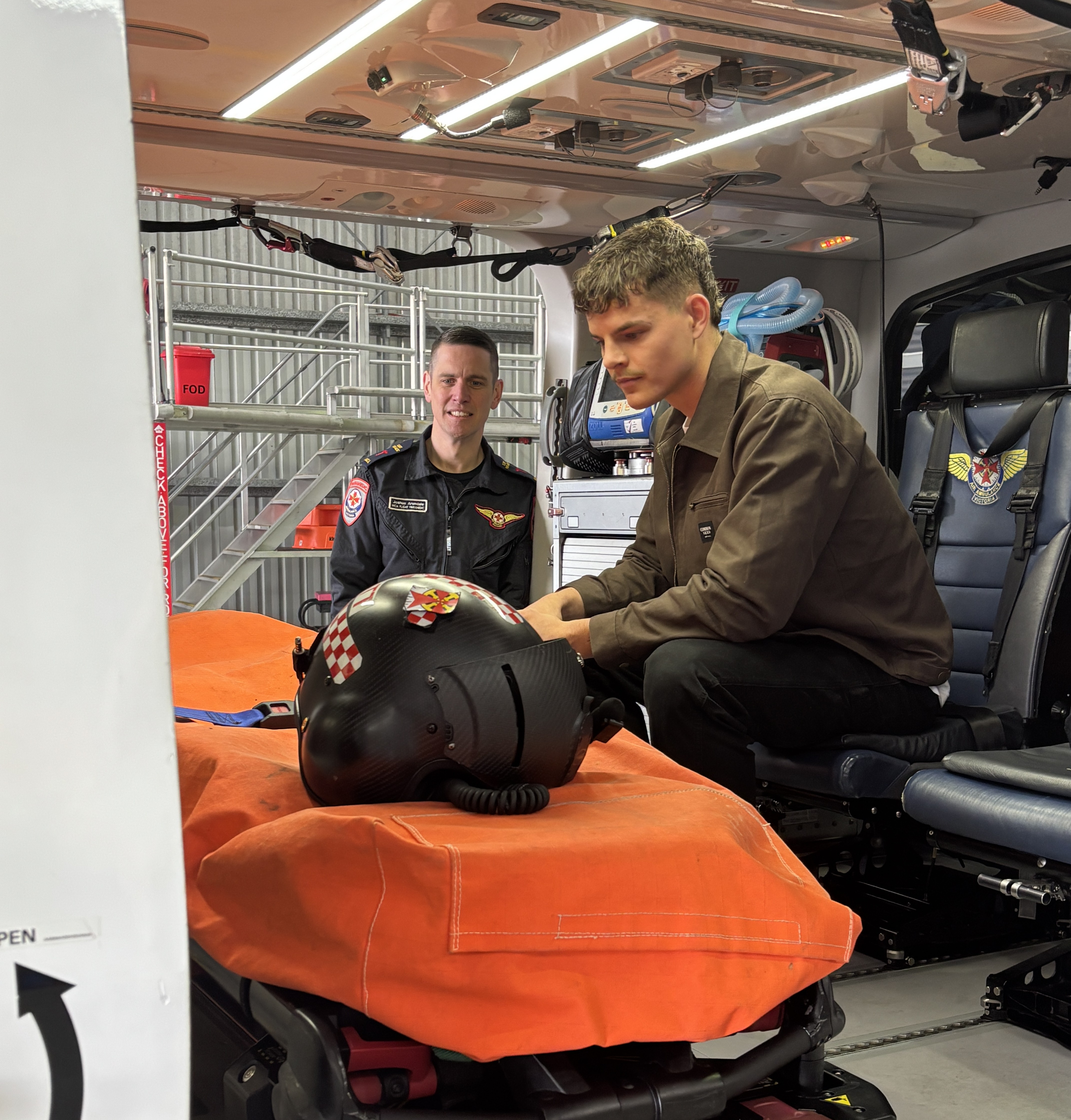Two men looking at the stretcher in the back of the ambulance helicopter.
